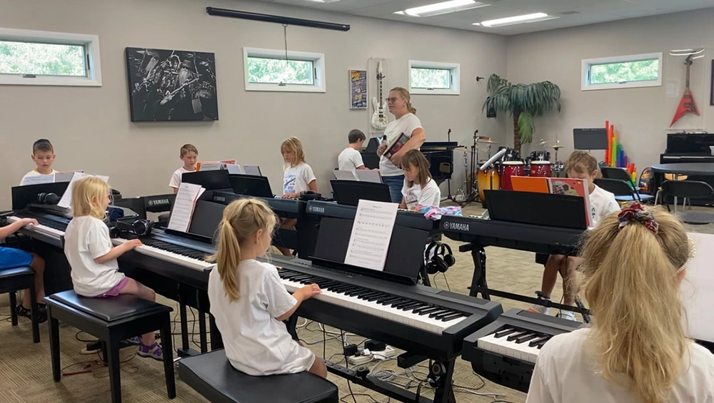 Surf Camp 2-v2 Students listening to a camp instructor in front of their pianos.
